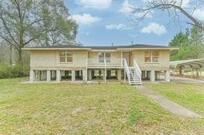 Front exterior of a raised one story home on piers with a carport, on an acreage lot in southeast Conroe, Texas