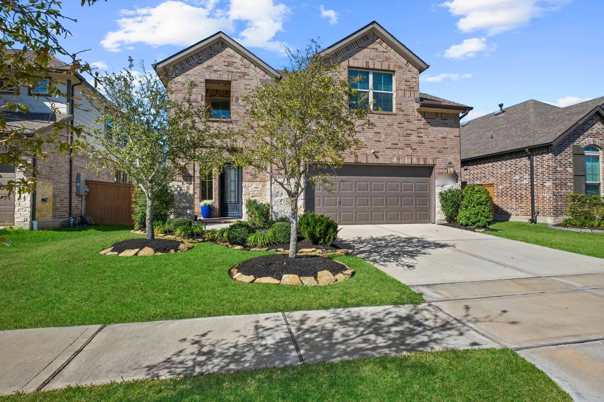 Front exterior of a two story brick and stone home with landscaped beds in Humble, Texas