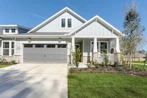 Front exterior of a light gray craftsman style new construction home with a covered porch in Porter, Texas
