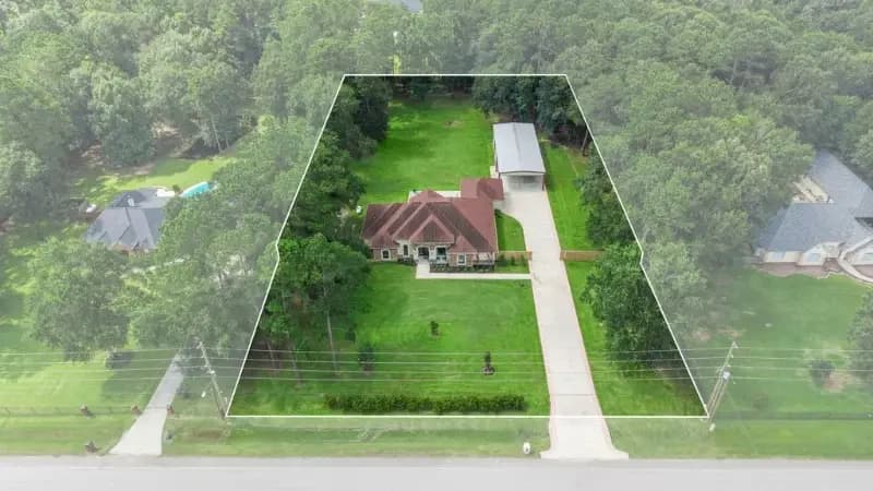 Aerial view of a one story home on a wooded acreage lot in the Riverwalk community, Porter, Texas