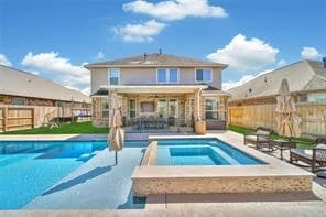 Backyard pool and spa with a covered patio behind a two story home in the Azalea District, Porter, Texas
